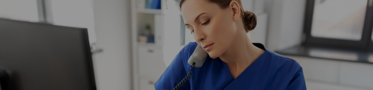 Infirmière au téléphone devant son poste de travail