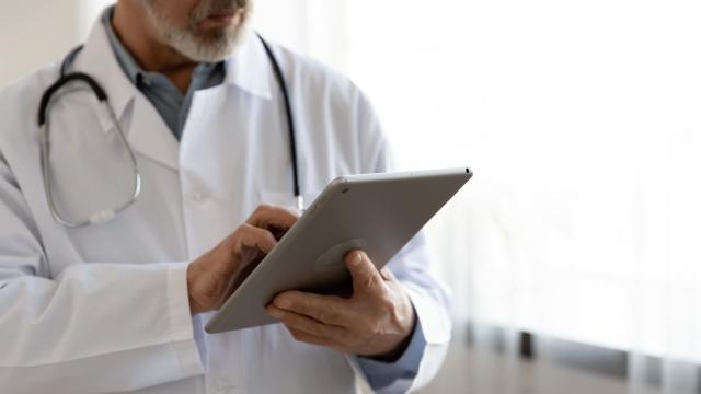 Médecin en tenue de travail avec stéthoscope autour du cou utilise sa tablette