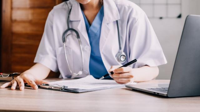 Médecin travaille dans son bureau et écrit sur un document