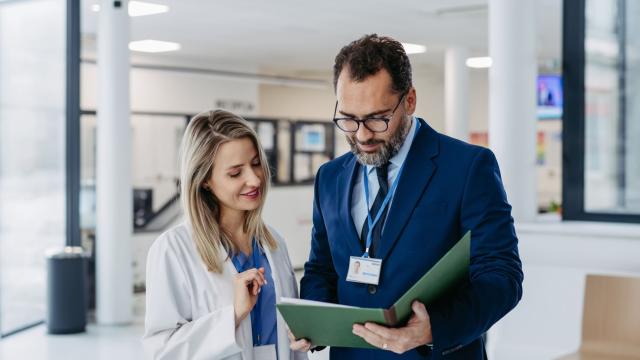 Deux personnes discutent ensemble et regardent des documents dans le cadre de leur travail