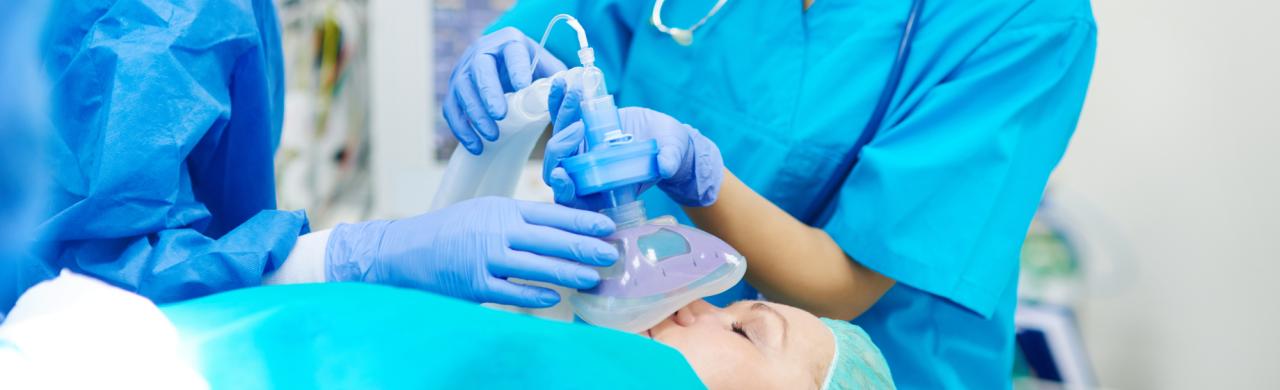 Infirmière anesthésiste prépare l'opération d'un patient allongé sur un lit d'hôpital dans un bloc opératoire
